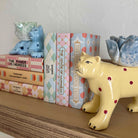 Ceramic animal figures and books on a shelf against a white wall