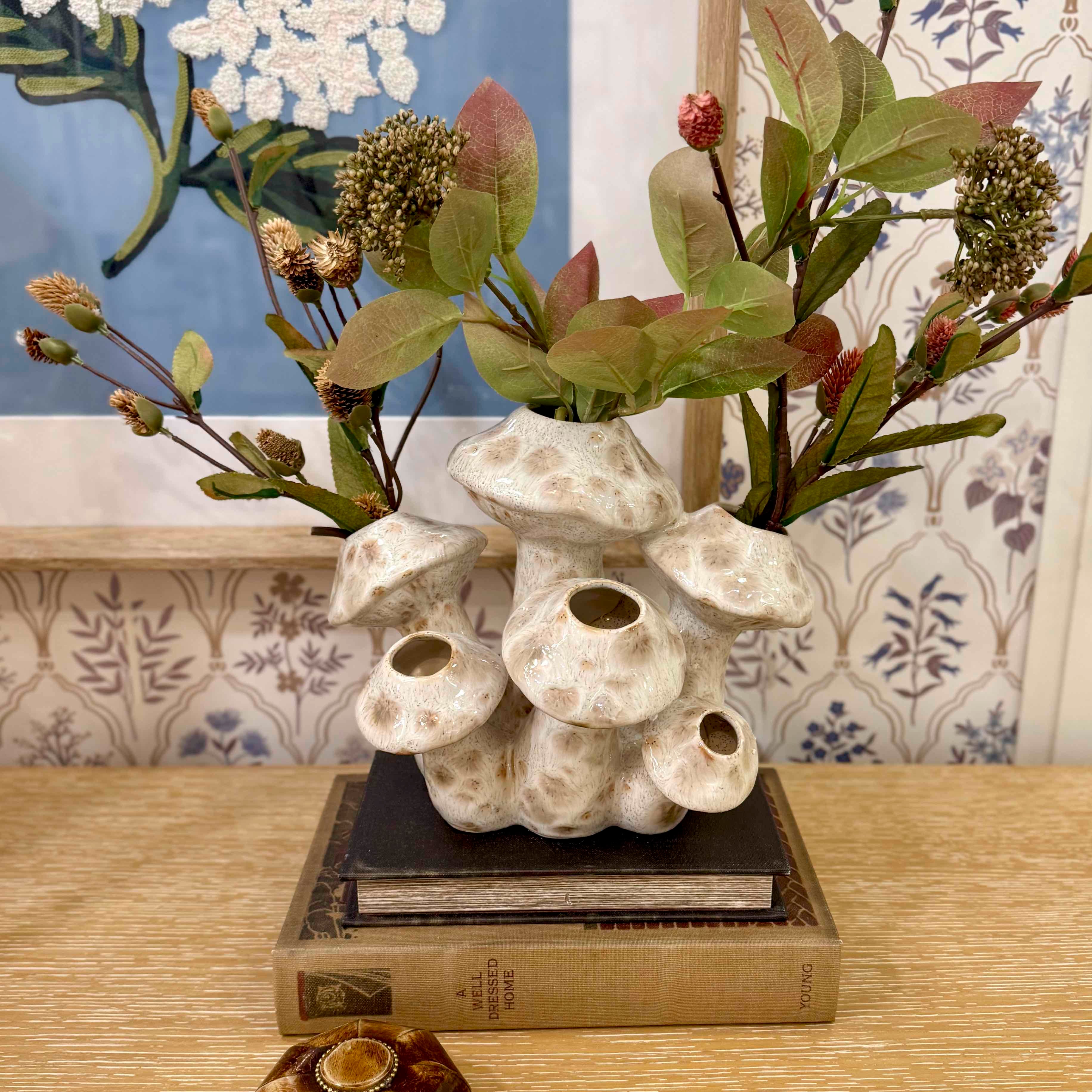 Decorative vase with plants on a table against a patterned wall