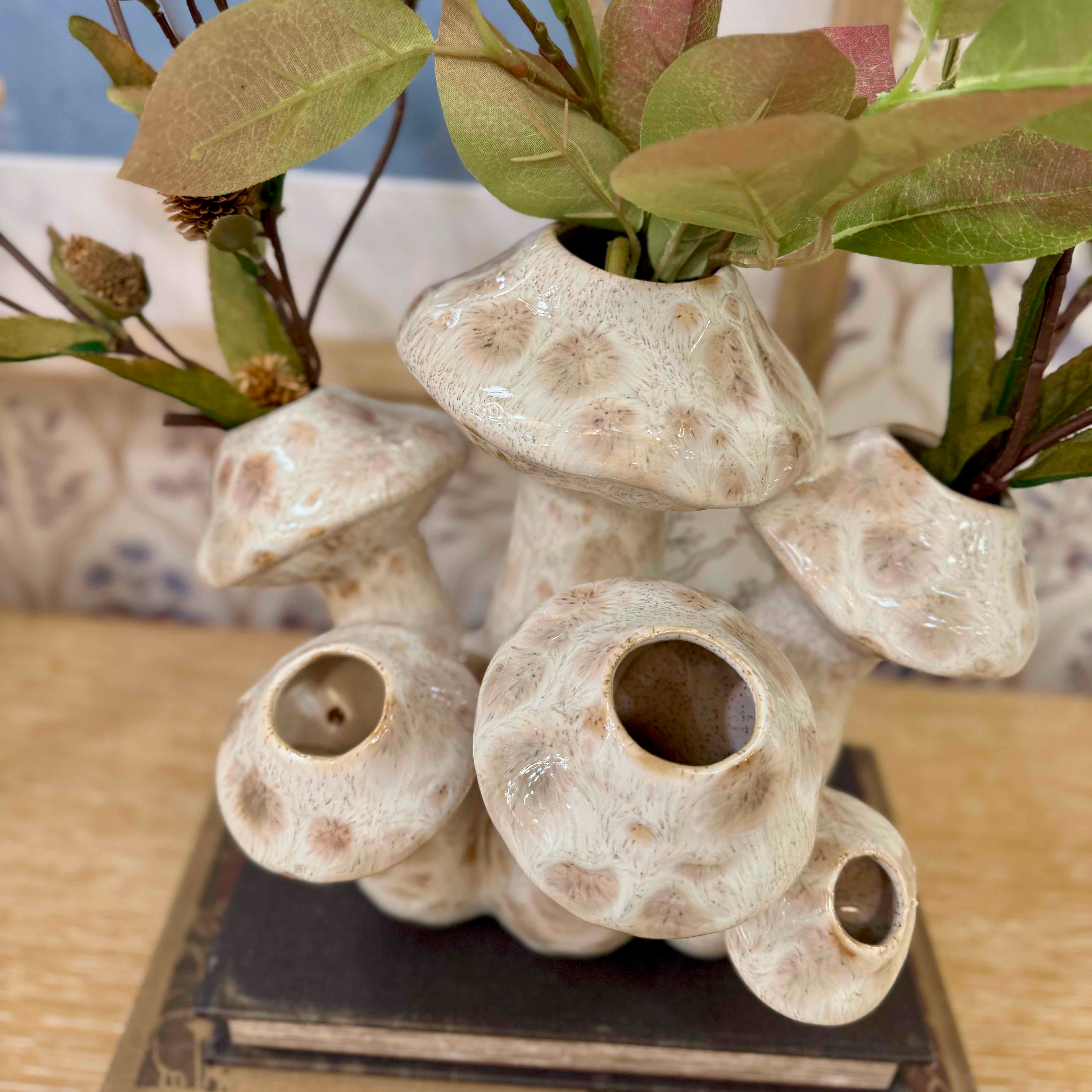 Ceramic vase with textured design and green leaves on a wooden surface