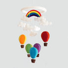 Colorful hot air balloon and rainbow mobile hanging against a light gray background