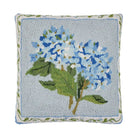 Decorative pillow with embroidered blue flowers and green leaves on a light blue background