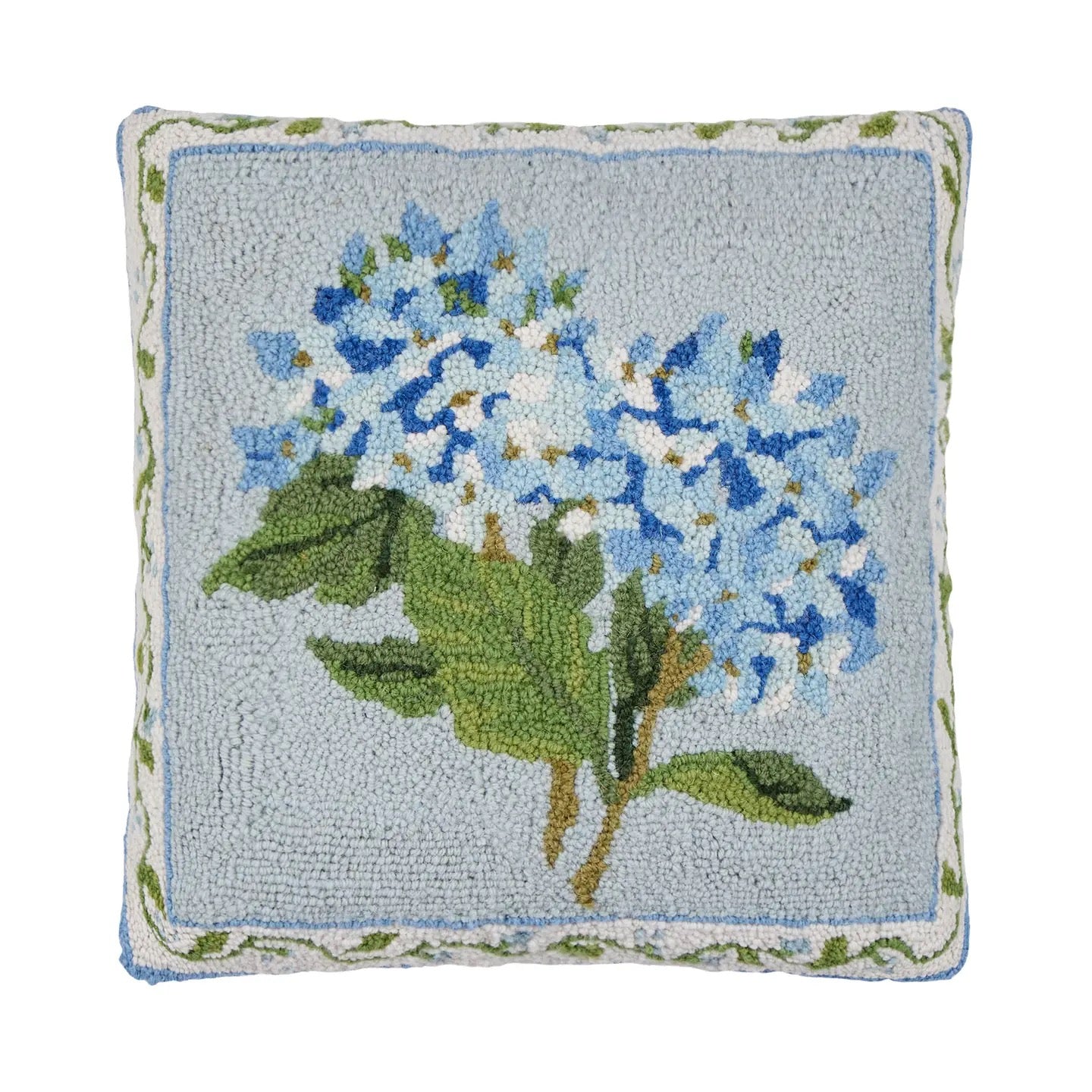 Decorative pillow with embroidered blue flowers and green leaves on a light blue background