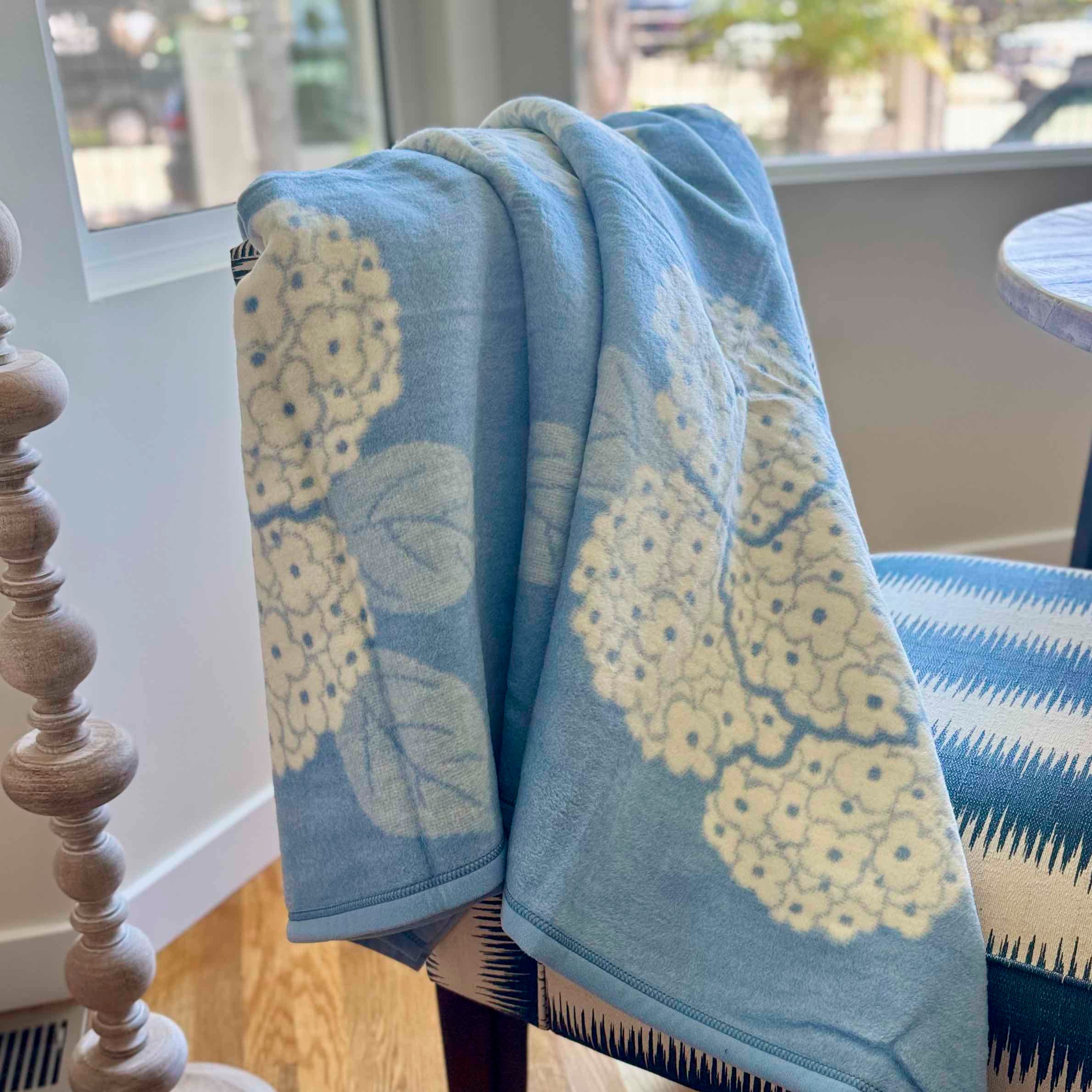 Blue towel with yellow floral pattern draped over a chair near a window.