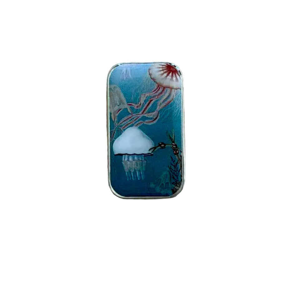 A small rectangular metal tin with a colorful jellyfish illustration, placed on a weathered wooden surface.