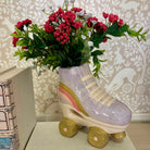 Roller skate-shaped vase with flowers against a decorative wall.