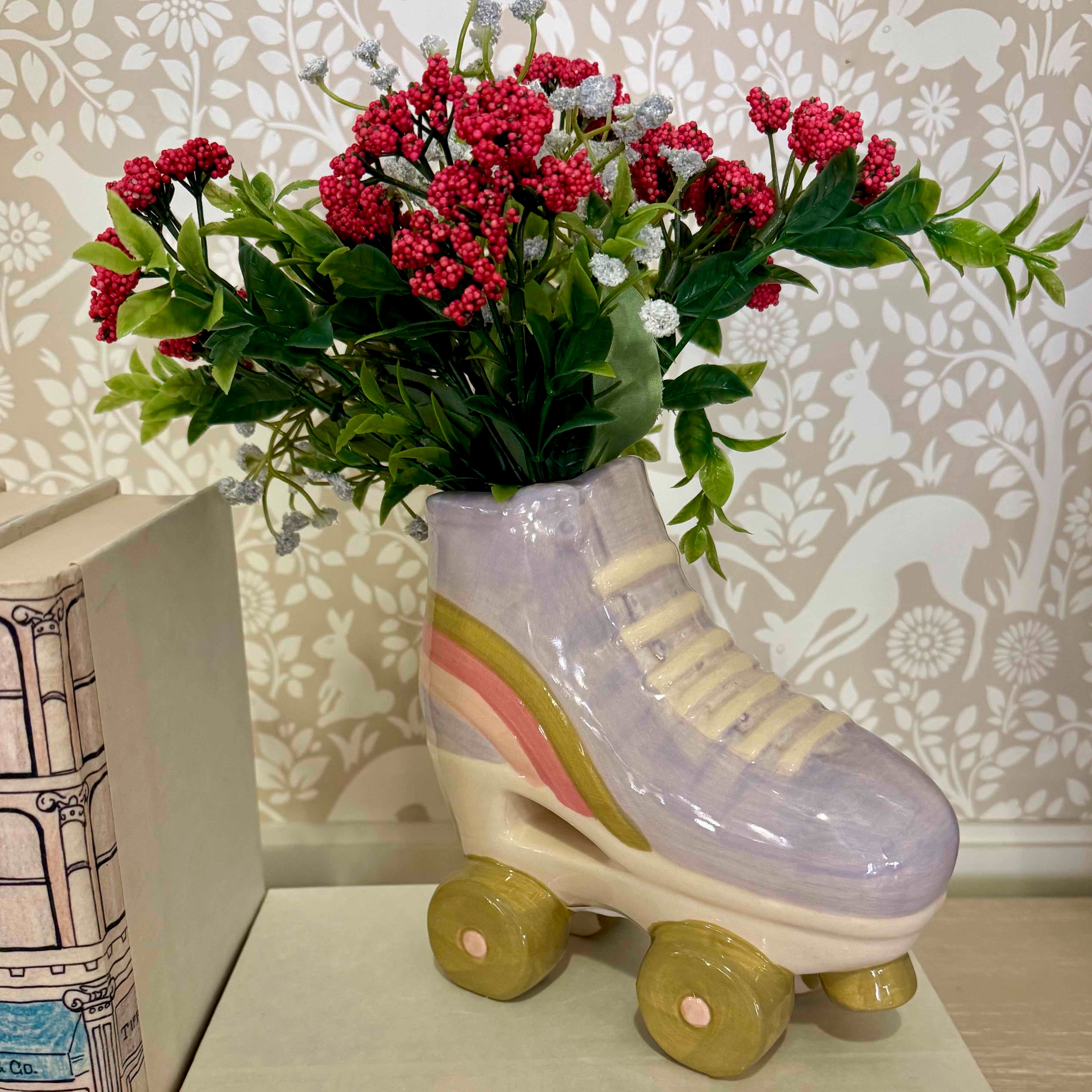 Roller skate-shaped vase with flowers against a decorative wall.
