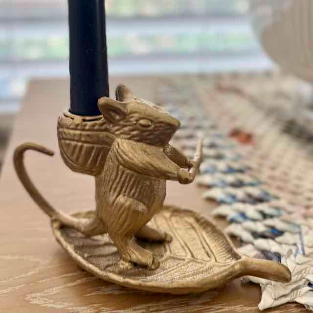 Brass mouse-shaped candle holder on a wooden surface