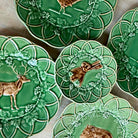Green ceramic plates with animal and nature designs on a wooden surface