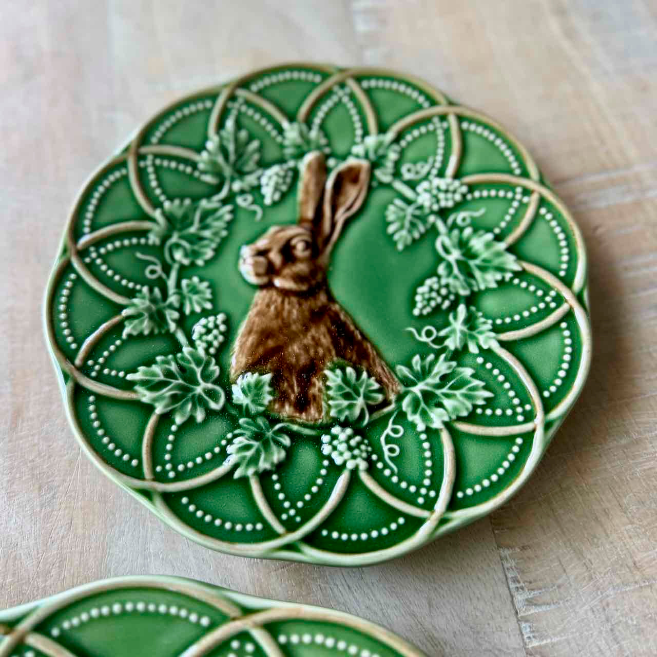 Decorative green plate with a rabbit design on a wooden surface