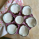Ceramic egg tray with purple rim on a wooden surface