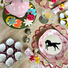 Dining table setting with decorative plates, glasses, and cutlery on a wooden surface.