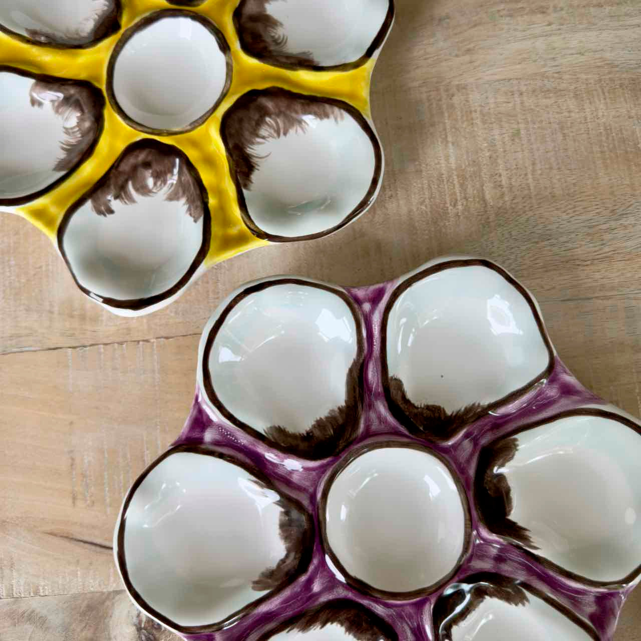 Two ceramic egg trays with white eggs on a wooden surface