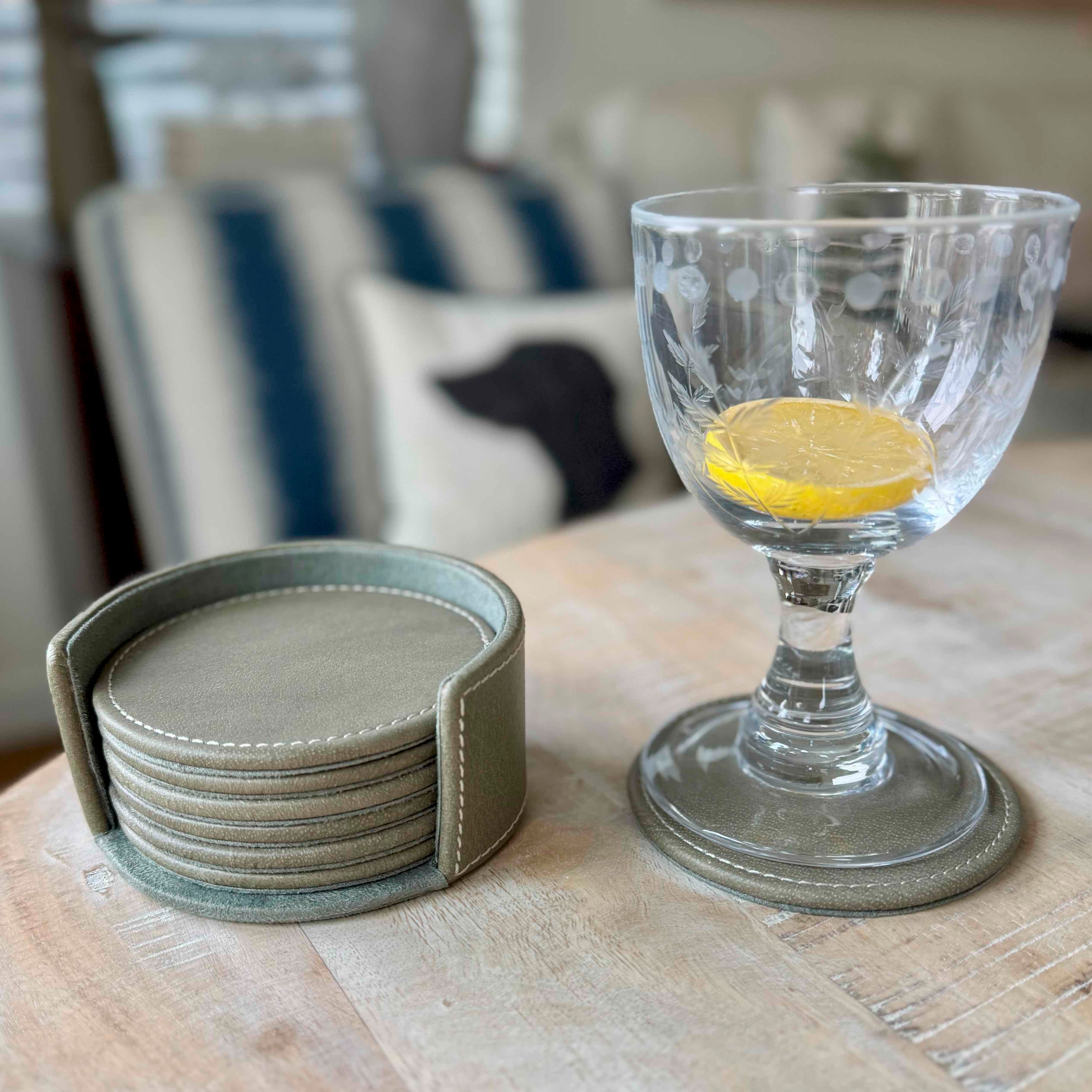 Clear glass with lemon slice and set of coasters on a wooden surface