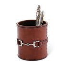 Brown leather holder with silver horsebit design containing a spoon on a white background