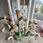 Decorative candle holder with floral design on a table with flowers and a blurred background