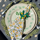 Set of tableware with lemon-themed napkins and cutlery on a decorative plate.