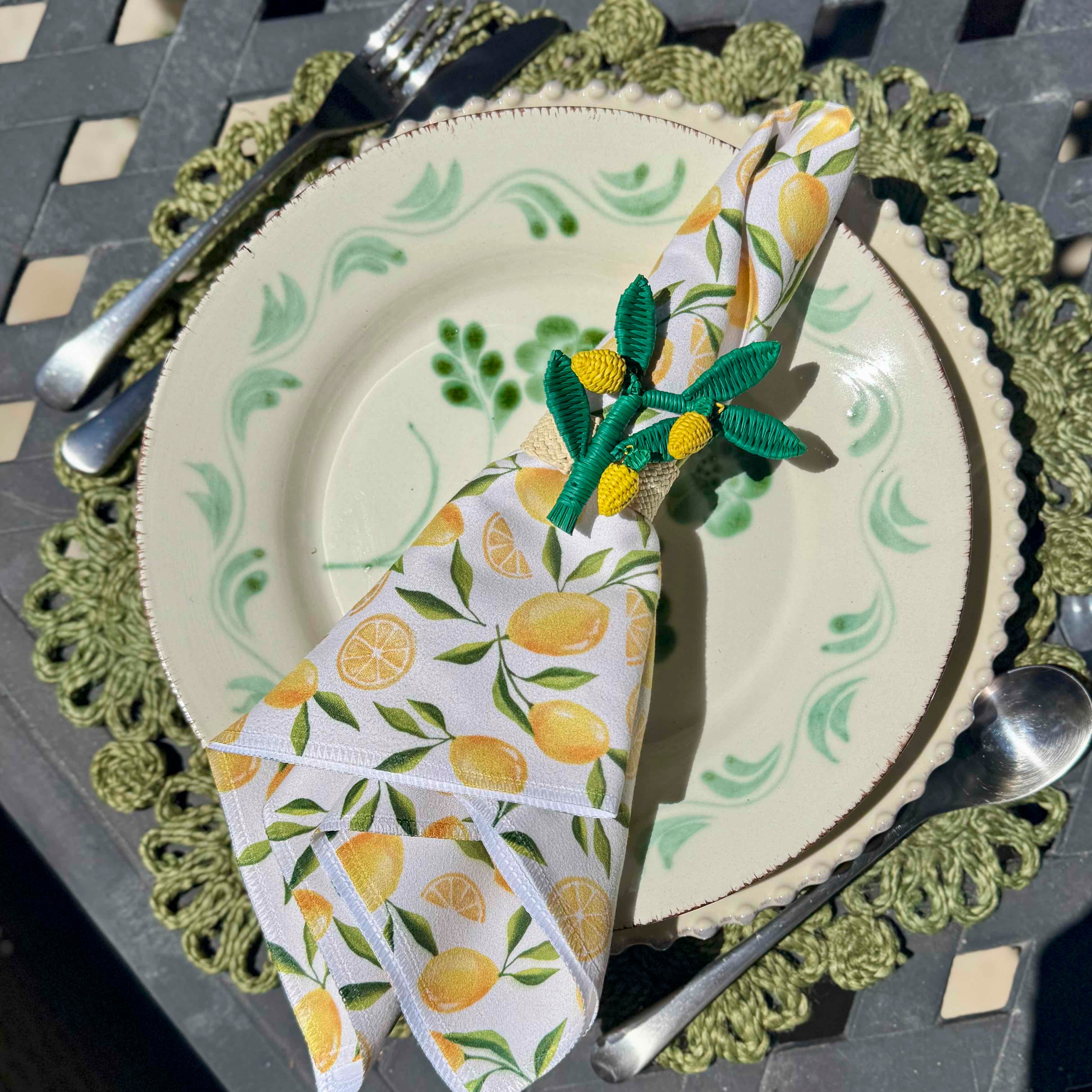 Set of tableware with lemon-themed napkins and cutlery on a decorative plate.