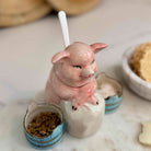 Ceramic piggy bank with a small bowl of coins on a marble surface