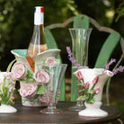 Decorative glassware and ceramic pieces with floral designs on a table outdoors.