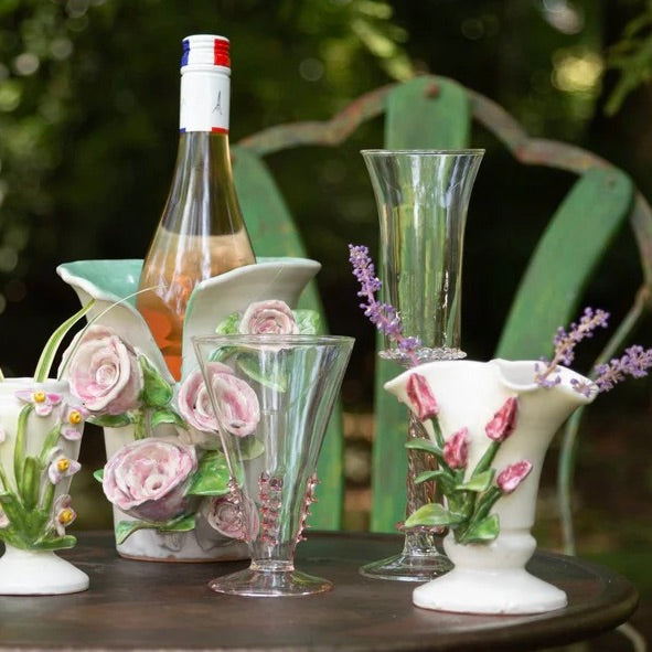 Decorative glassware and ceramic pieces with floral designs on a table outdoors.