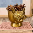 Gold owl-shaped container with pinecones on a decorative surface