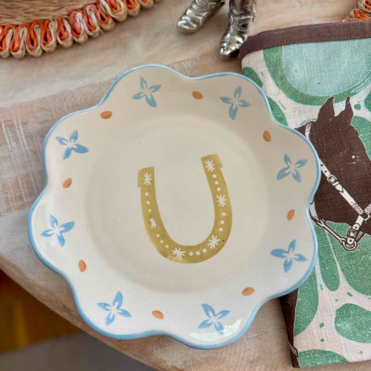 Decorative plate with a horseshoe design on a surface with horse-themed items.