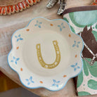 Decorative plate with a horseshoe design on a surface with horse-themed items.