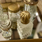 Decorative glass bottles with gold caps on a reflective surface