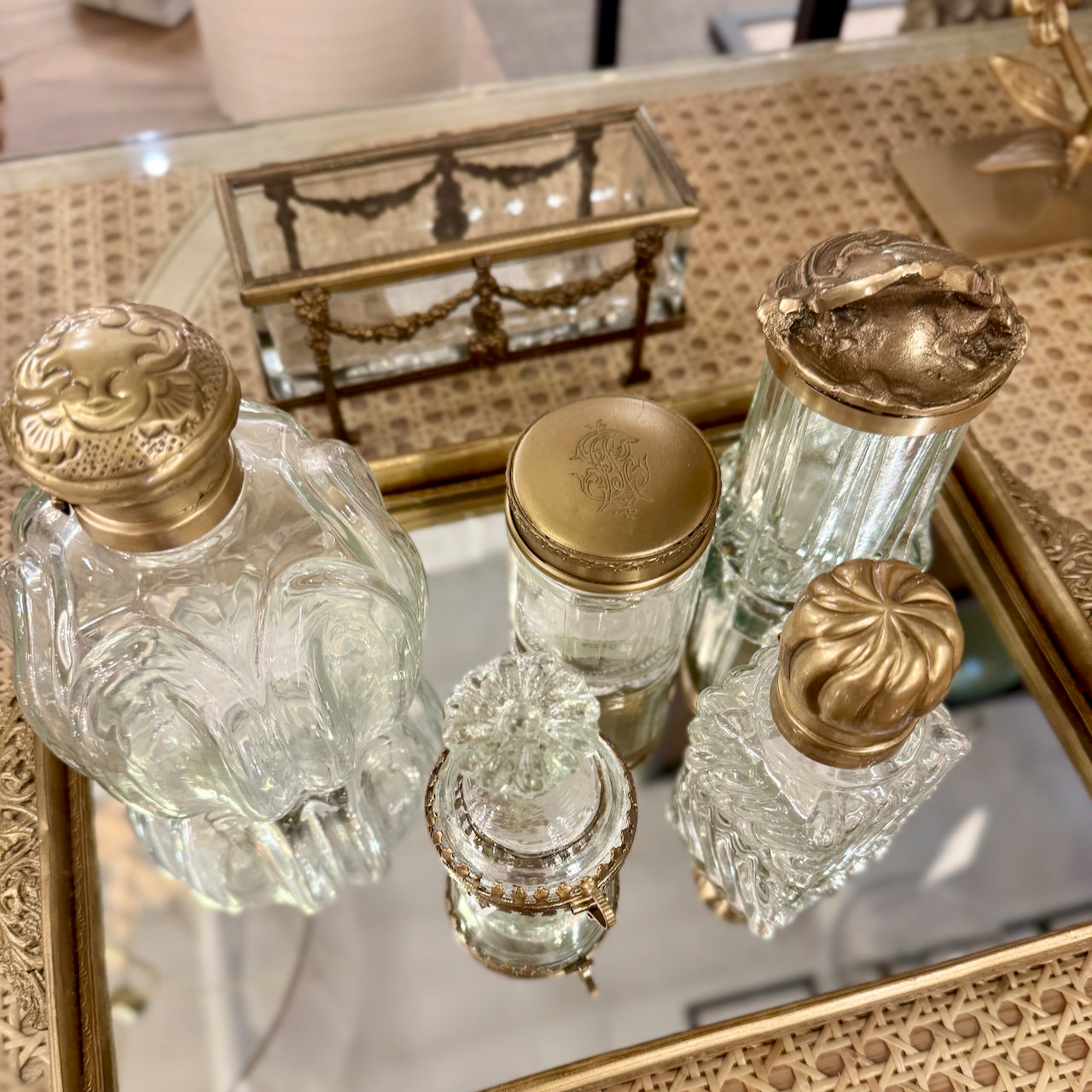 Set of decorative glass bottles with gold lids on a reflective surface