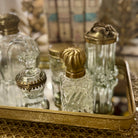 Vintage glass perfume bottles with gold caps on a decorative tray.