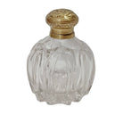 Clear glass perfume bottle with a gold cap on a white background