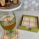 Glass of beer on a checkered napkin with a box of plaid napkins in the background.