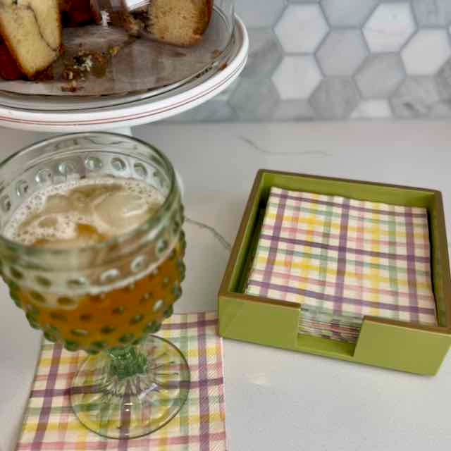 Glass of beer on a checkered napkin with a box of plaid napkins in the background.