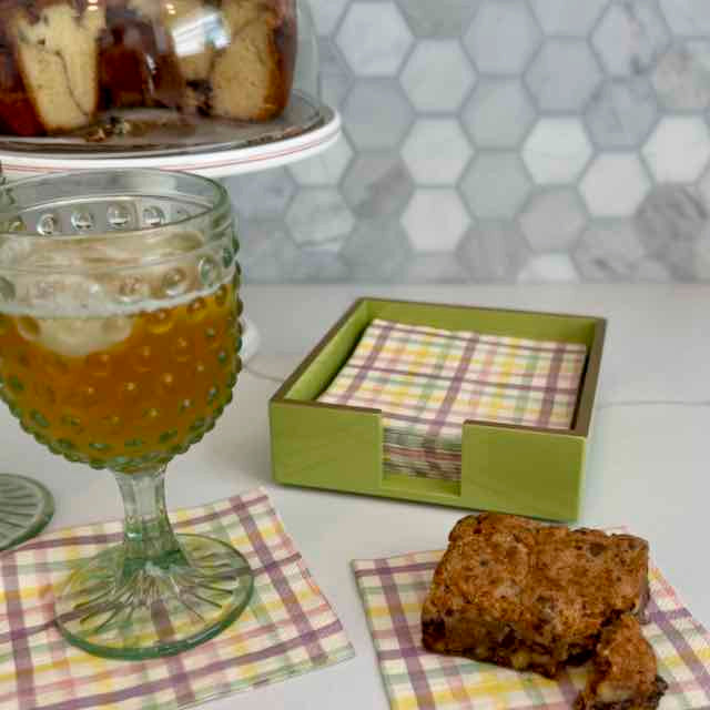 Glass of iced tea with a cake and napkins on a table.
