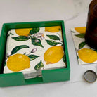 Set of lemon-patterned napkins in a green box on a white surface.
