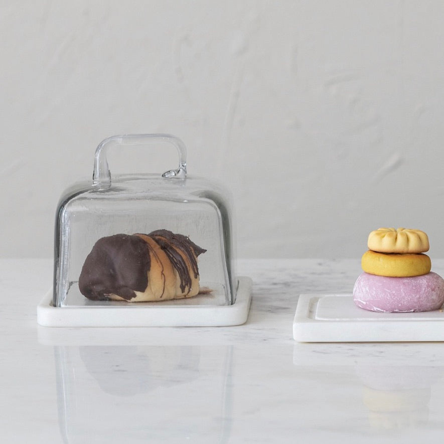 Glass cake stand with a loaf of bread on a marble surface