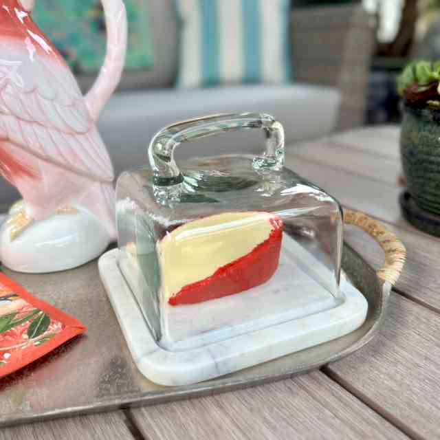 Butter dish with a slice of bread on a marble base, placed on a wooden surface.