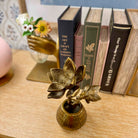 Bronze lotus flower sculpture on a wooden surface with books in the background
