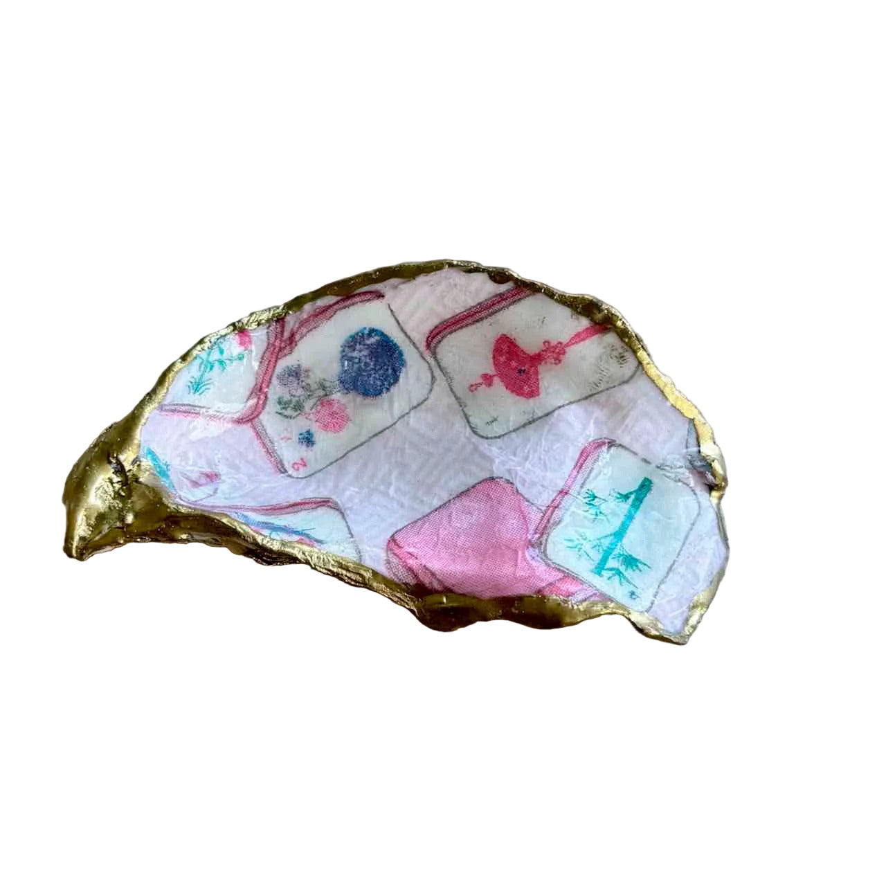 A handmade gold-rimmed shell-shaped dish or tray decorated with colorful printed tile patterns on a light wood background.