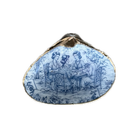 A shell-shaped ring featuring a blue and white illustration of three women playing cards, bordered by a gold-toned metal edge.