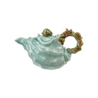 Ceramic teapot shaped like a shell with a handle on a white background