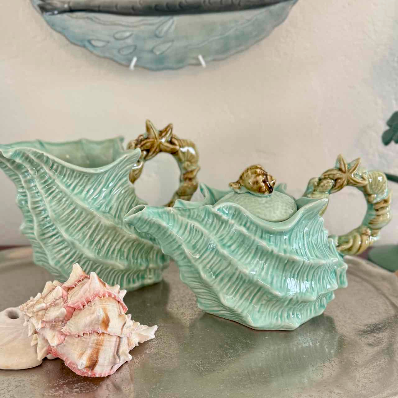 Decorative ceramic shell pieces with a small real shell on a neutral background