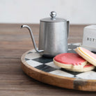 Silver teapot on a checkered tray with cookies
