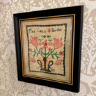 Framed artwork with floral design and text on a patterned wall