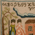 Embroidered scene with two figures, a house, and text on a textured fabric background.