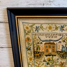 Framed needlepoint with decorative elements on a wooden surface