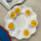 White egg platter with deviled eggs on a gray surface