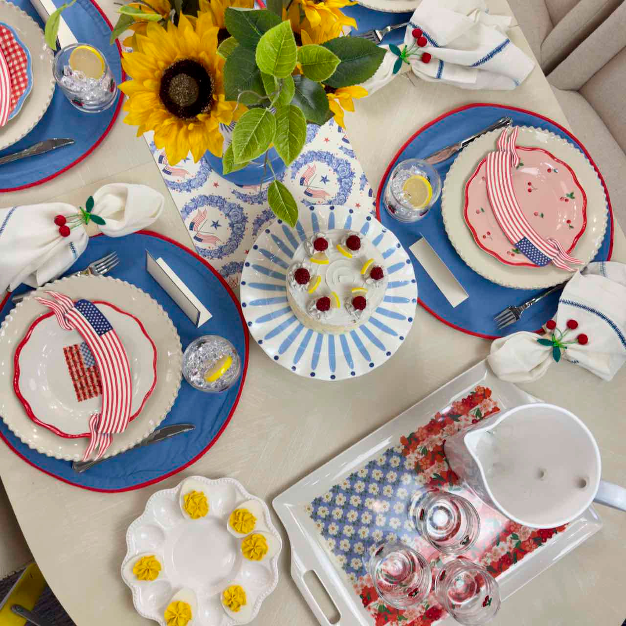 Dining table set with festive plates, napkins, and centerpieces on a light-colored surface.