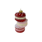 A stacked set of three macaron-shaped ornaments in red, pink, and light pink, decorated with white pearls and a small gold bell ornament on top, set against a plain white background.