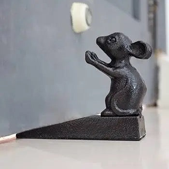Black cast iron mouse-shaped door stopper on a surface with a neutral background
